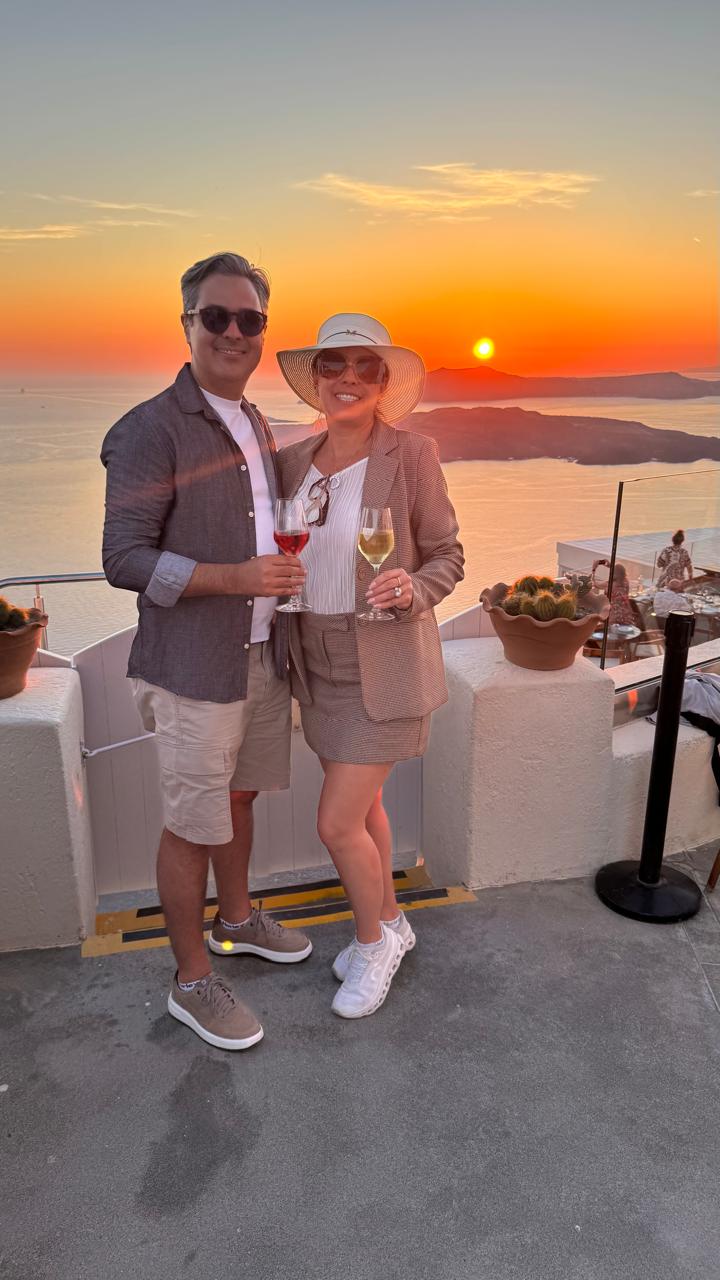 O casal brindando ao pôr do sol em Santorini